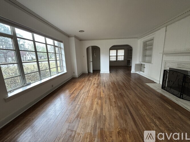 A spacious room with wooden floors and large windows.