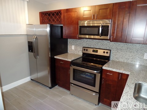 A kitchen with a stainless steel refrigerator and a black microwave above the stove.