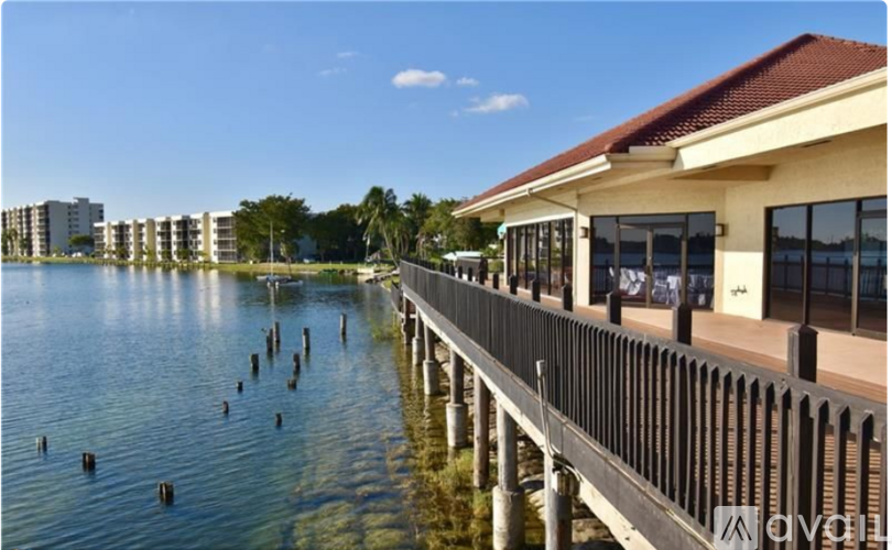 A wooden pier extends into a body of water with buildings in the background.