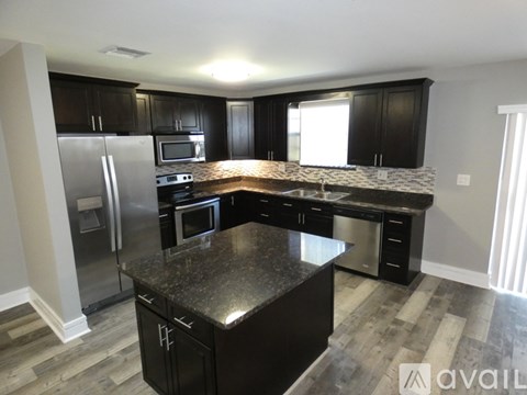 A kitchen with black cabinets and granite countertops.