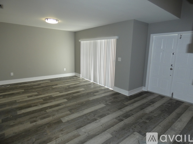 A room with wooden flooring and a white door.