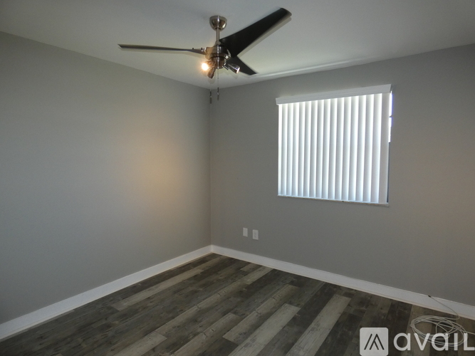 A room with a ceiling fan and a window with blinds.