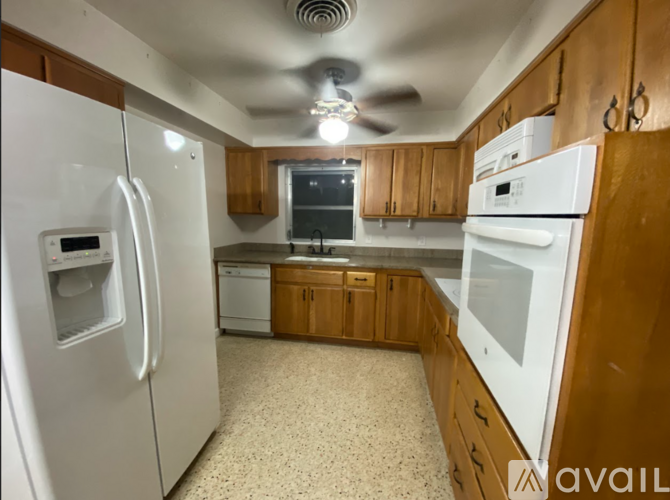 A kitchen with white appliances and wooden cabinets.