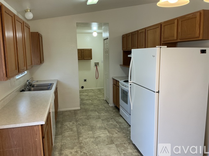 A kitchen with a white refrigerator and wooden cabinets.