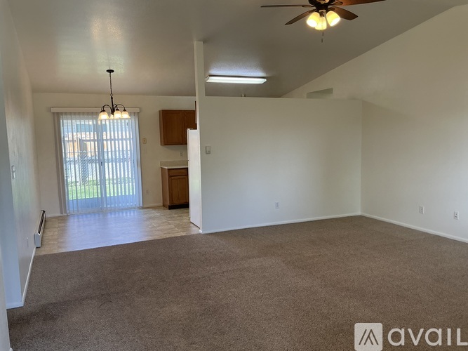 A spacious room with a ceiling fan and carpeted floor.