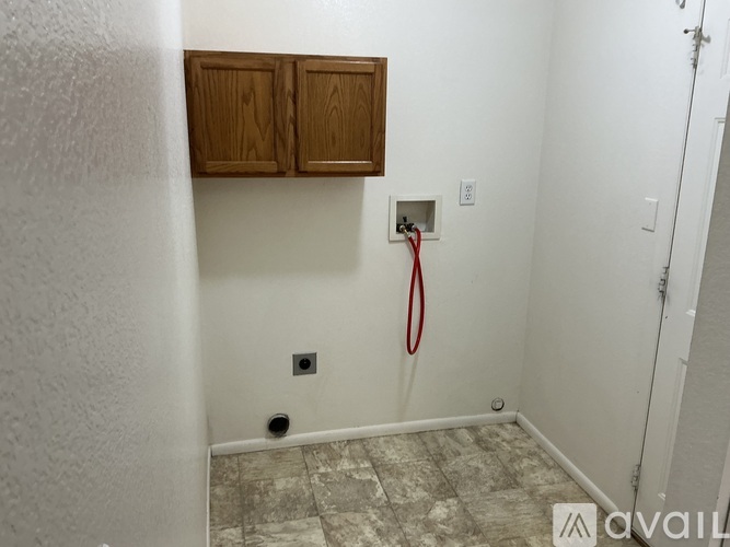 A bathroom with a red hose and wooden cabinets.