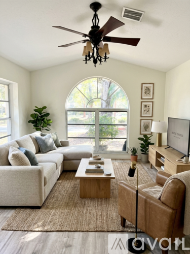 A living room with a couch, a coffee table, a television, and a ceiling fan.