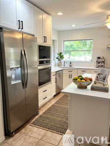 A kitchen with a stainless steel refrigerator and white cabinets.