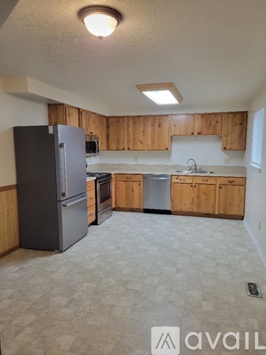 A kitchen with wooden cabinets and a black fridge.