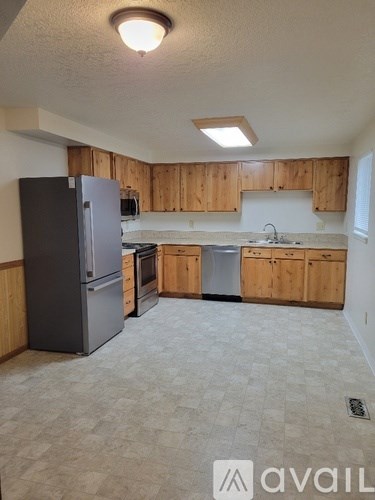 A kitchen with wooden cabinets and a black fridge.