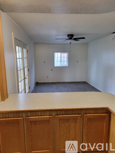 A room with a window and a fan on the ceiling.