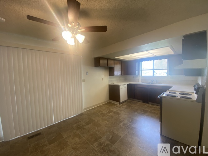 A room with a fan, a window, and a kitchenette.