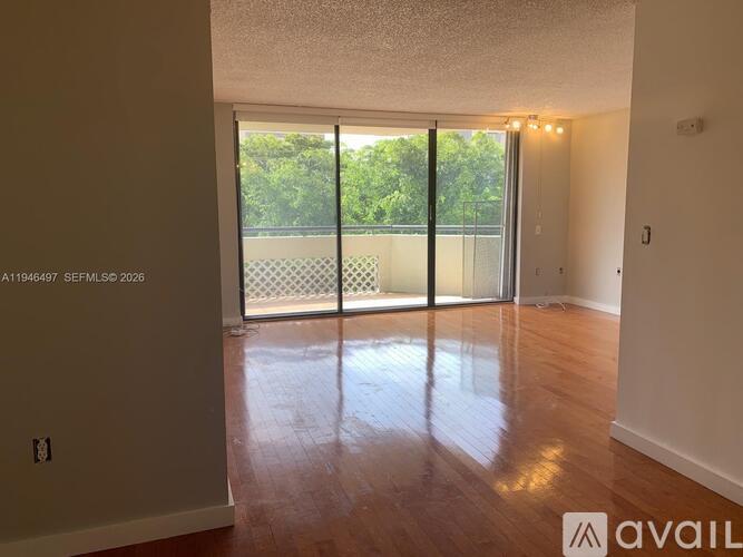 A room with wooden floors and a sliding glass door leading to a balcony.