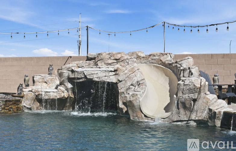 A water slide in a pool with a rocky wall and a slide entrance.