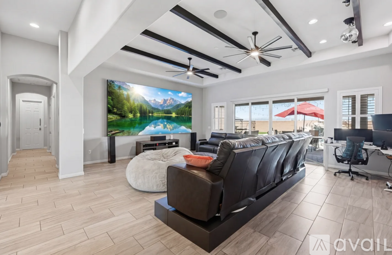 A modern living room with a large painting on the wall and a black sofa.