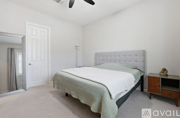 A bedroom with a large bed and a ceiling fan.