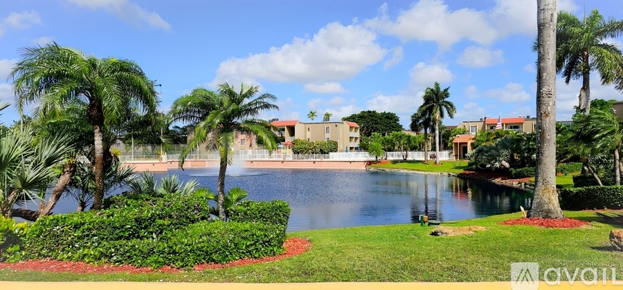 A beautiful landscape with a lake, palm trees and a building in the background.