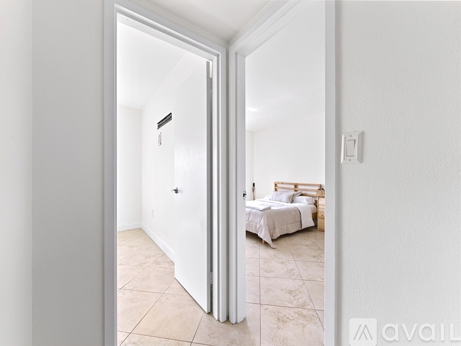 A bedroom with a bed and a nightstand is visible through an open door.