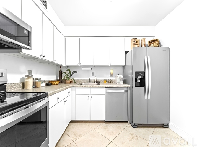 A kitchen with white cabinets and a stainless steel refrigerator.