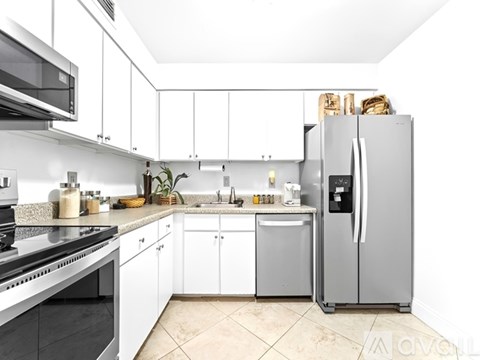 A kitchen with white cabinets and a stainless steel refrigerator.