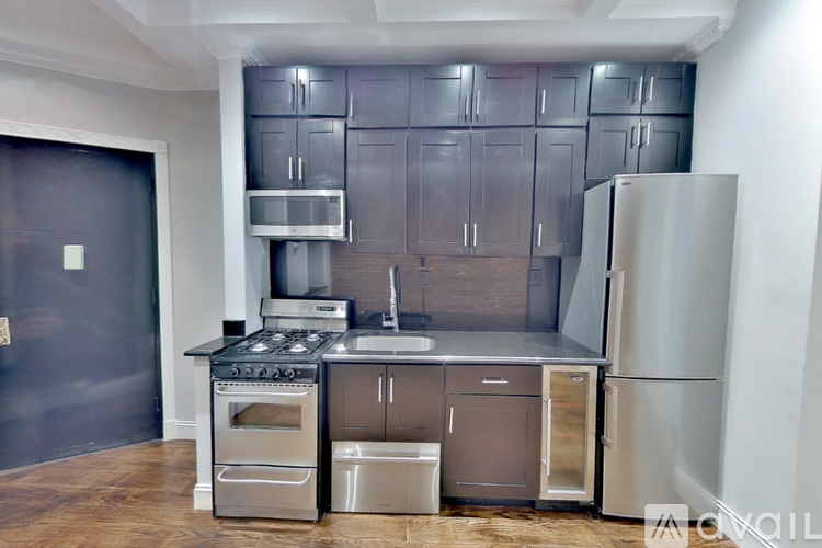 A kitchen with stainless steel appliances and a wooden floor.