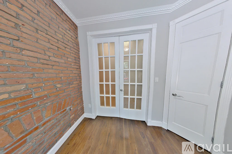 A room with a white door and a brick wall.