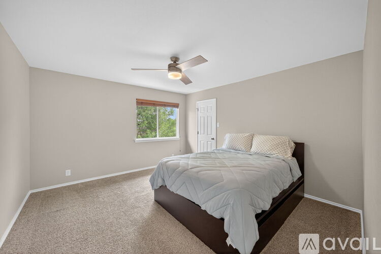 A bedroom with a bed, carpeted floor, and a window.