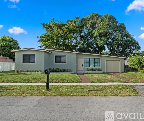A house with a grey roof and a white fence is for sale.