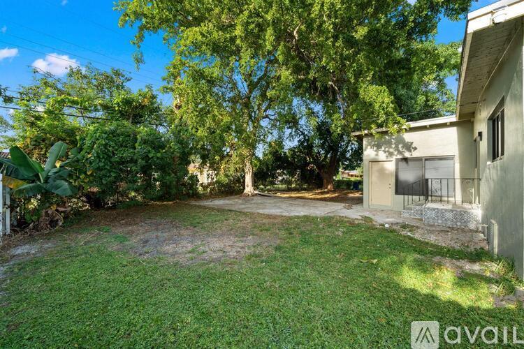 A backyard with a house, trees, and a lawn.
