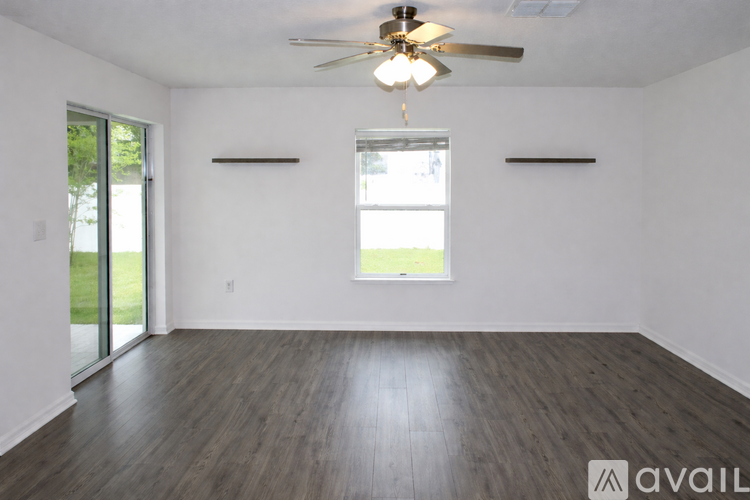 A spacious room with a ceiling fan and sliding glass doors.