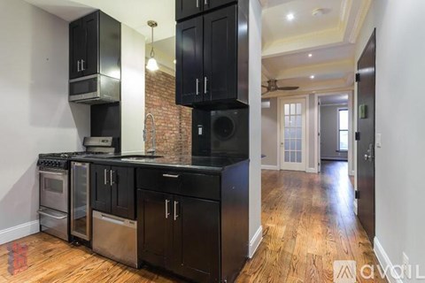 A kitchen with black cabinets and a brick wall.