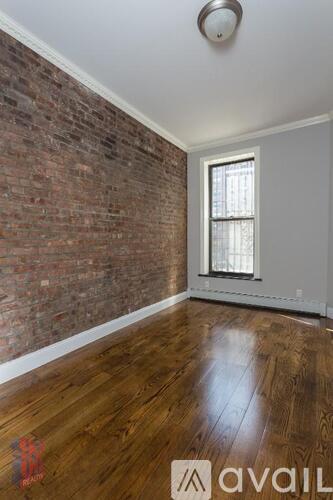 A room with a wooden floor and a brick wall.