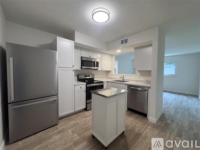 A kitchen with a refrigerator, microwave, oven, sink, and dishwasher.