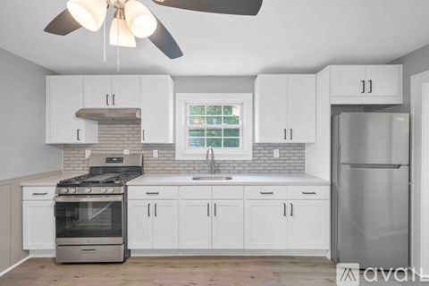A kitchen with white cabinets and a stainless steel refrigerator.