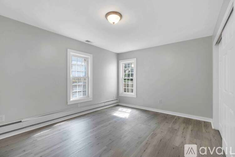 A room with wooden floors and two windows.