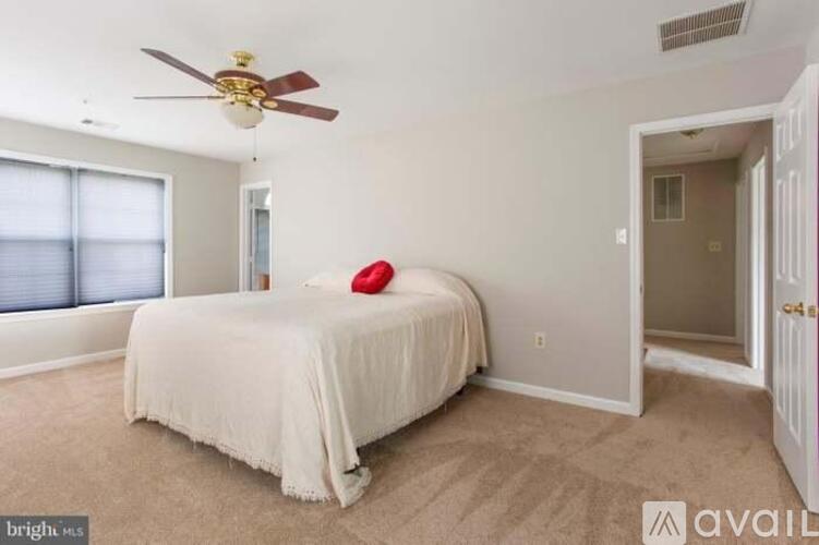 A bedroom with a bed, a ceiling fan, and a carpeted floor.