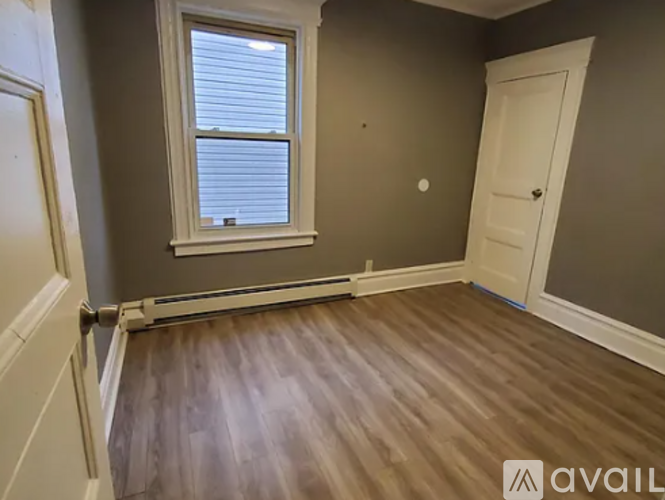 A room with a window and wooden flooring.