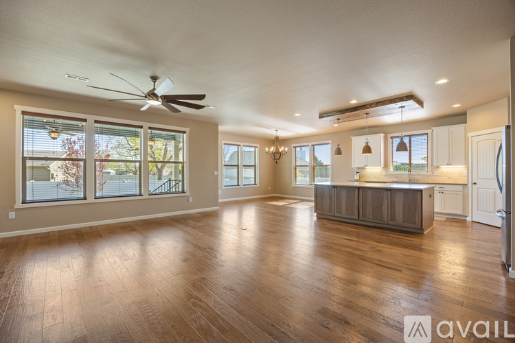 A spacious living room with hardwood floors and a ceiling fan.
