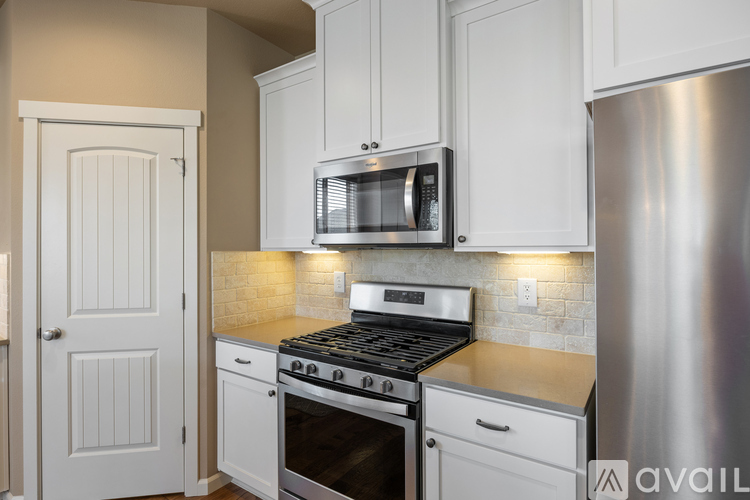 A kitchen with a stainless steel refrigerator, a microwave above the stove, and white cabinets.