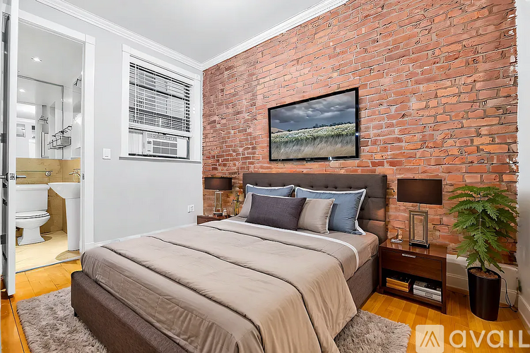A bedroom with a brick wall and a bed.