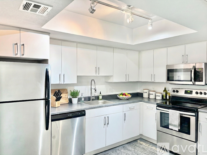 A modern kitchen with white cabinets and stainless steel appliances.