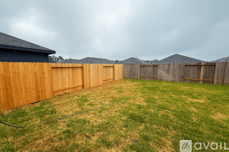 A backyard with a wooden fence and a grassy area.
