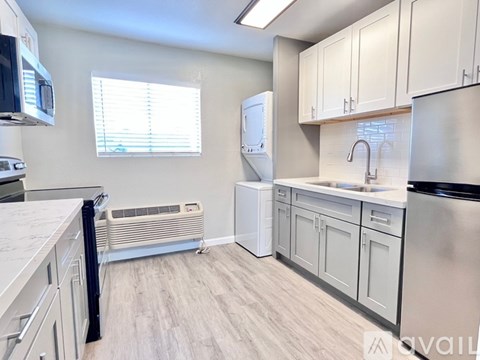 A kitchen with white cabinets and a stainless steel refrigerator.