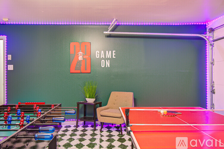 A room with a foosball table, a pool table, and a chair.