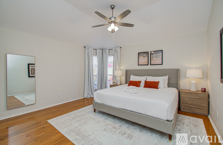 A bedroom with a large bed, a ceiling fan, and a rug on the floor.