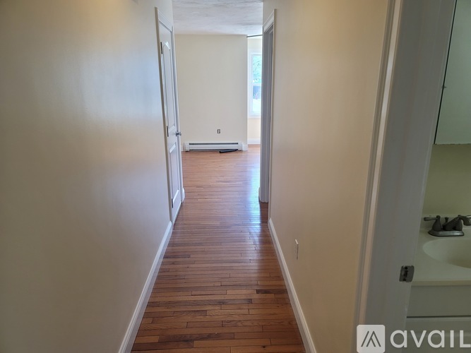 A hallway with wood floors and white walls.