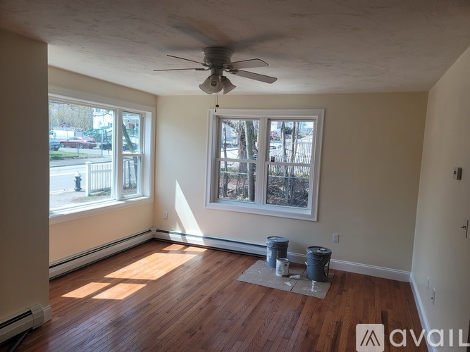 A room with a ceiling fan and a window with a view of a street.