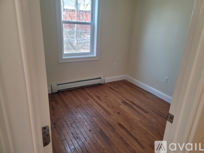 A room with wooden flooring and a window.
