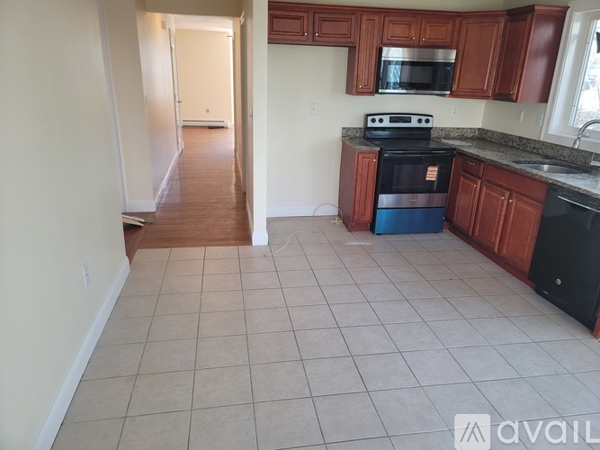 A kitchen with brown cabinets and a black dishwasher.