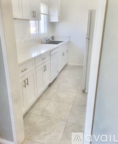 A kitchen with white cabinets and a tiled floor.
